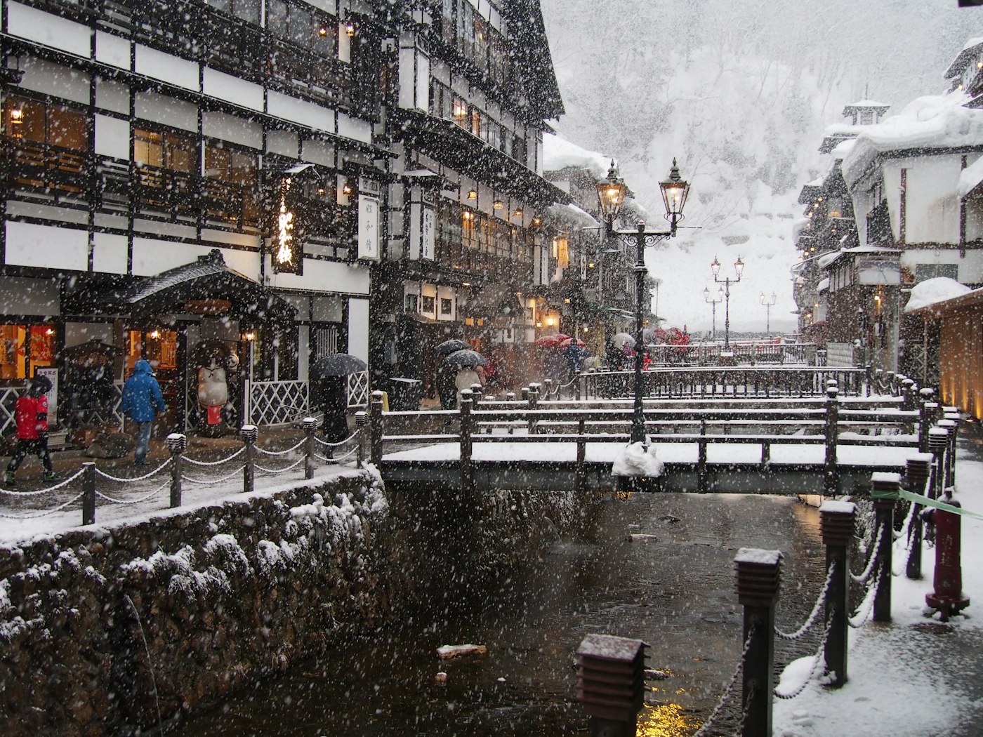 Heavy snowfall over the central bridge and wooden inns of Ginzan Onsen in daytime