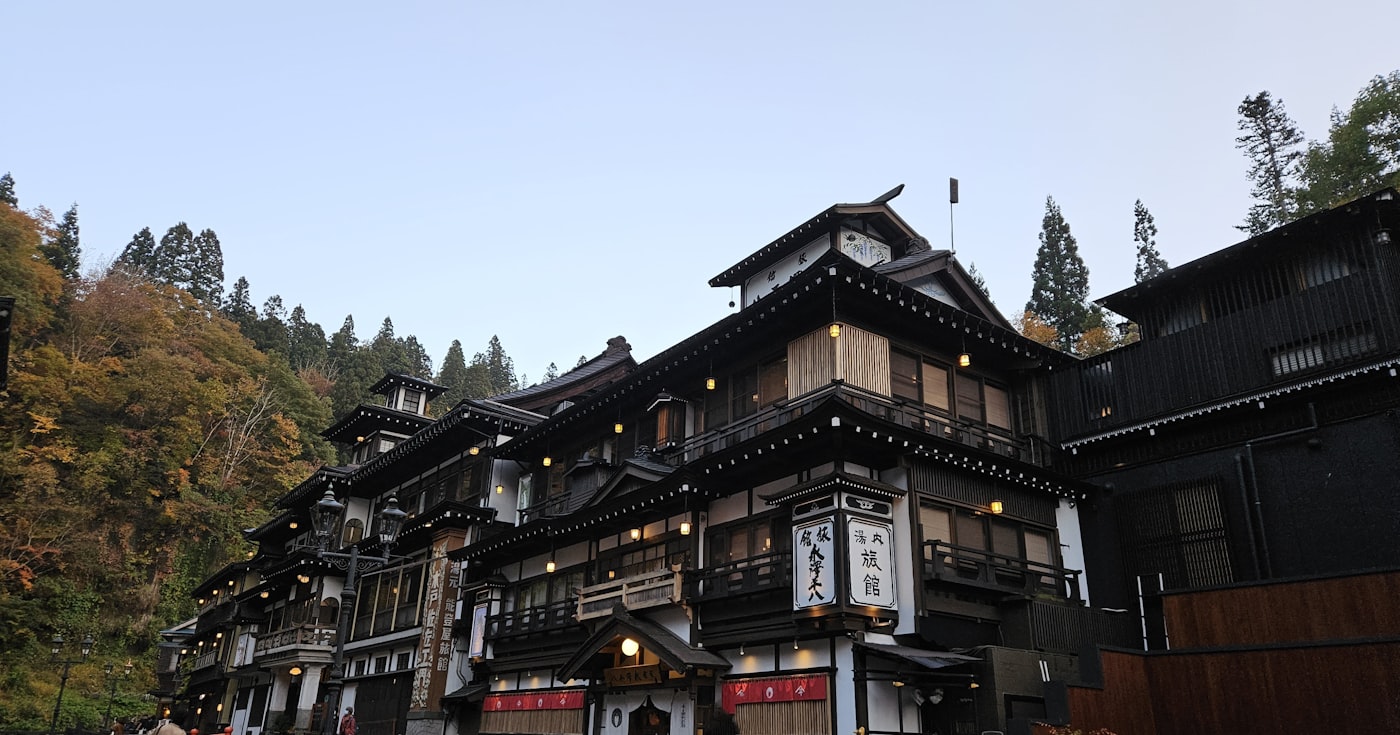 The wooden inns of Ginzan Onsen in autumn, lamps just lit, no snow